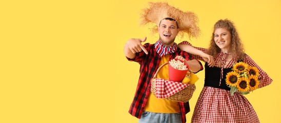 Happy young couple with popcorn and sunflowers on yellow background with space for text. Banner for Festa Junina (June Festival)