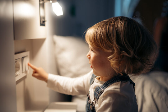 Curious toddler reaching for light switch in bedroom - Powered by Adobe