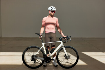 Cyclist poses confidently with road bike in modern indoor settin