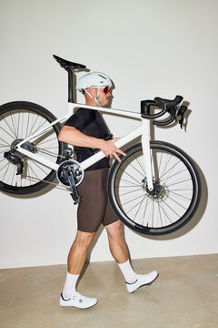 Cyclist carries bicycle indoors after workout session