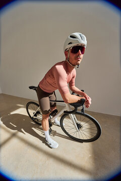 Cyclist posing with bike indoors during daylight hours