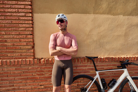 Cyclist relaxing against wall in urban setting at daytime