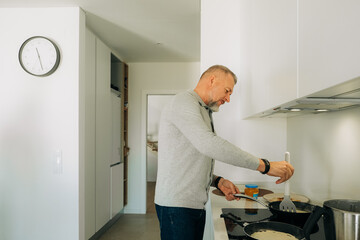 Man flipping pancakes on stovetop in home kitchen