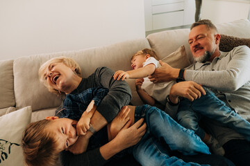 Grandparents Tickling and Playing with Laughing Kids on Couch