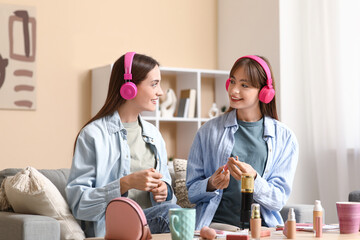 Young sisters in headphones with makeup products recording podcast at home