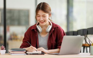 Young asian happy smiling Hispanic Asian student wearing headphones talking on online chat meeting...