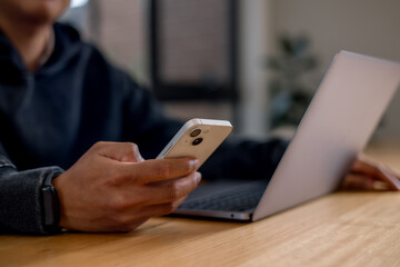 businessman using a smartphone while sitting at a desk with a laptop in a modern office environment.using artificial intelligence smart apps