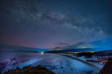 Frozen lake and falling stars in winter night. Milky way and meteor stars over the Lake baikal, Siberia, Russia.