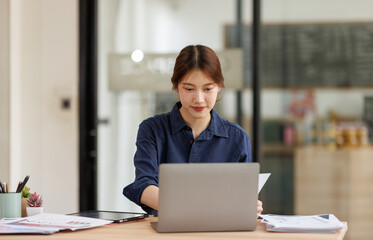 Annual, summary report, laptop and paper placed at office desk. Asian woman work online and plan financial data with laptop, work in the office. Business woman and planner concept
