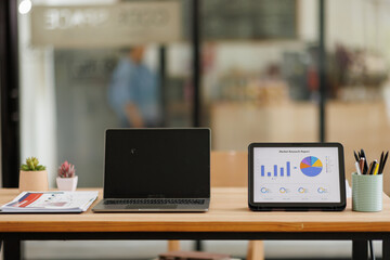 Tablet Laptop Computer, notebook, and eyeglasses sitting on a desk in a large open plan office...