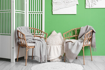 Plaid, armchairs and folding screen in interior of beautiful living room