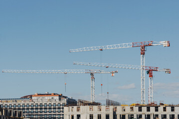 construction cranes stand above building under construction, panoramic view, urban development concept