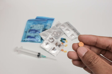 Close-up of a hand holding a single tablet with blurred medical supplies in the background