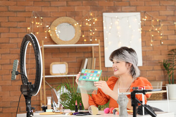 Female beauty blogger with eyeshadows recording video at home