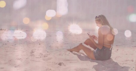 Woman scrolling smartphone on sandy beach at sunset, showcasing mobile marketing icons and charts