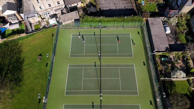 Clevedon Lawn Tennis Club with active match and surrounding gardens rooftops and suburban buildings