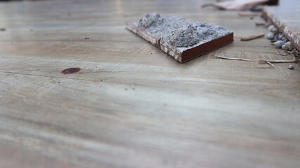 Damaged outdoor tile floor with cracks, scattered leaves and rough surface texture.