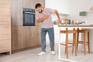 Young man having heart attack near table at home
