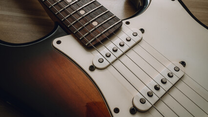 Close-up of electric guitar strings and pickups. Vintage style detail showing texture and craftsmanship of a classic musical instrument. Perfect for music, rock, or retro themes.