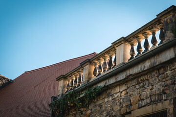 Fototapeta premium Delicate stone balustrade adorned with intricate designs against the clear blue sky in a historic village setting