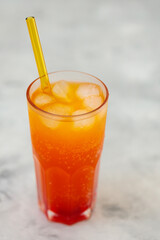 Refreshing Orange Carbonated Drink with Ice Cubes in Tall Glass on Gray Surface, Trendy Dirty Soda Concept