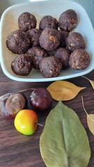 Chickpea and nut candies lie on a plate and nearby are leaves and chestnuts for decoration