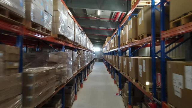 Camera moving through warehouse aisles filled with cardboard boxes on metal shelves, showcasing storage and logistics