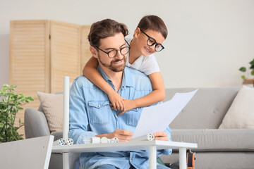 Father with instructions and his little son assembling shelf unit at home