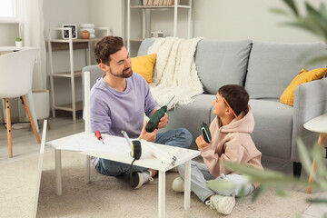 Father and his little son with instruments assembling shelf unit at home
