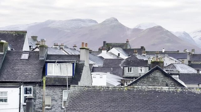 View of iconic fell Catbells perched above rooftops of Keswick town on a snowy winter's morning - Lake District, UK