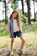 Cute smiling preschool girl with dandelion in her hair outdoors
