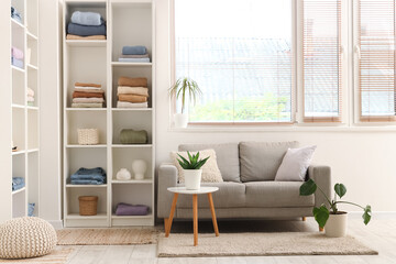 Stylish interior of light room with folded clothes in shelving units