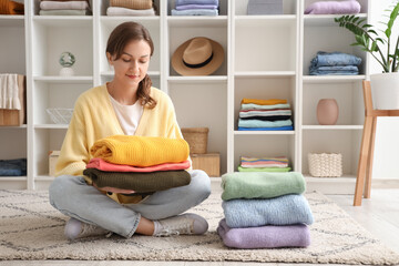 Young woman sitting on floor with clothes in dressing room