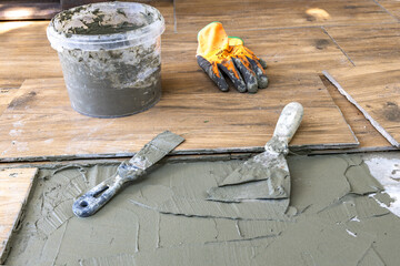 Laying tiles on a terrace in the garden, gluing tiles with frost-resistant glue on a veranda under a pergola
