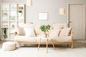 Interior of light living room with beige sofa, table and shelf unit