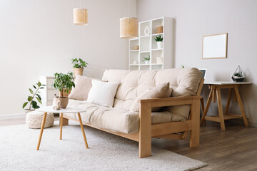 Interior of light living room with beige sofa, table and shelf unit
