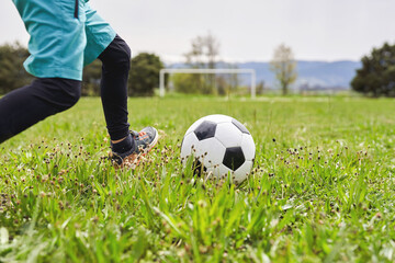 Child kicking soccer ball on green field during training session