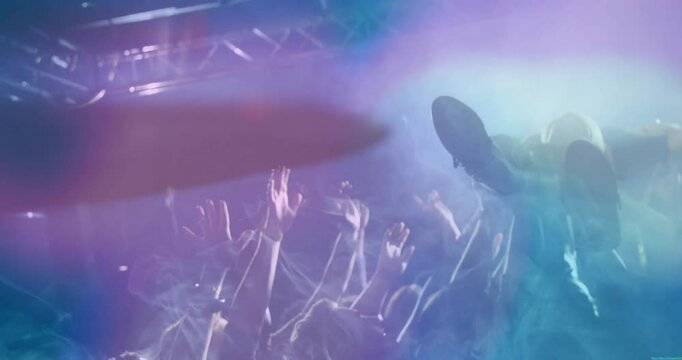 Concert fans reaching toward diving performer, showing music marketing with smoke, colored lights