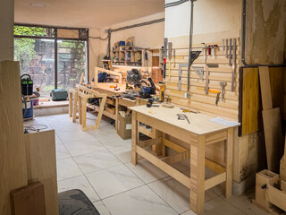 Spacious woodworking studio with tables, frames, tool racks, bright walls, power saws, and crafting stations ready for construction and DIY building.