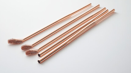 Trio of rose-gold reusable straws with a cleaning brush presented on a white background