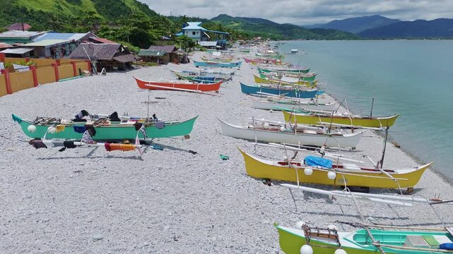 Mabua Pebble beach, Surigao Philippines. Rows of Banca fishing boats in bright colors wait out the midday sun and heat.