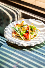 A beautifully plated dish featuring grilled vegetables and fish, garnished with herbs and a drizzle of sauce, presented elegantly on a decorative plate.
