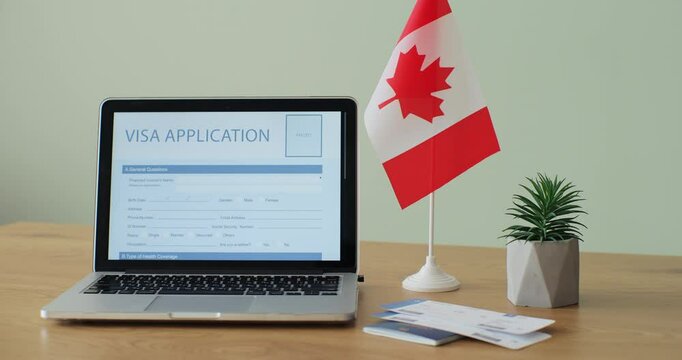 Online Canada Visa Application showing on a laptop computer screen sitting on a desk. Travelling abroad or immigration concept.