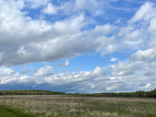 Beautiful spring sky with clouds over empty fields and greenery.