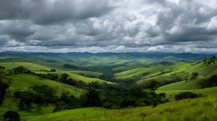 Fototapeta premium A scenic view of rolling green hills under a cloudy sky with distant mountain ranges in the background