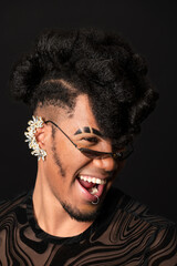 Young stylish man with extravagant hairstyle is laughing and wearing sunglasses and an earring
