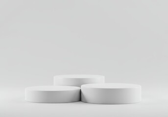 Three white cylindrical podiums arranged in a tiered display against a neutral backdrop for product placement