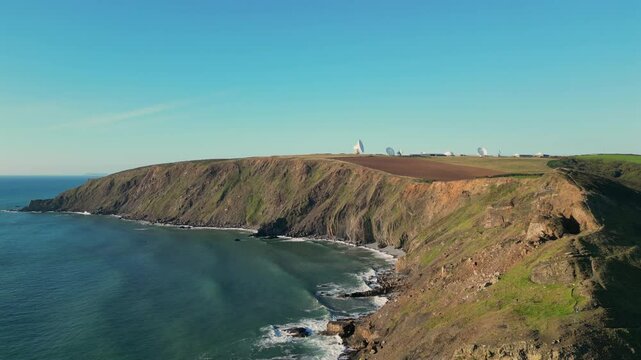 Aerial view of Duckpool Beach rugged cliffs and serene blue sea, waves meeting stone