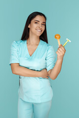 Cosmetologist holding sugaring paste and razor for depilation procedure over blue background