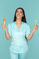 Cosmetologist holding sugaring paste and razor for depilation procedure over blue background